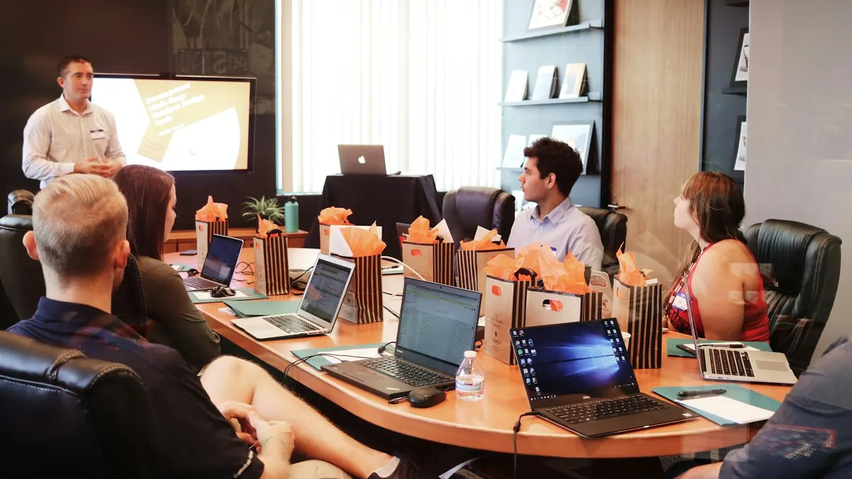 A team of colleagues gathered around a conference table with laptops during an agency presentation